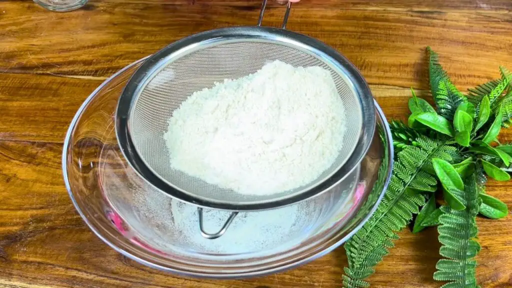 Flour, baking powder, baking soda, and salt being sifted together for the sugar free date cake recipe to make the batter smooth and lump free.
