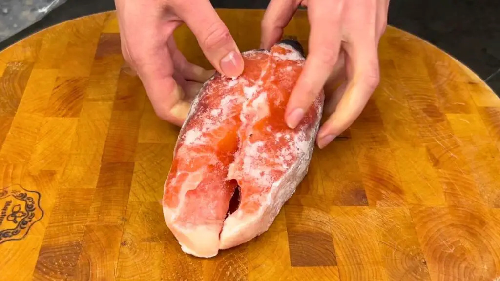 Frozen salmon steak on a cutting board for how to cook frozen salmon in air fryer tips and common mistakes to avoid.