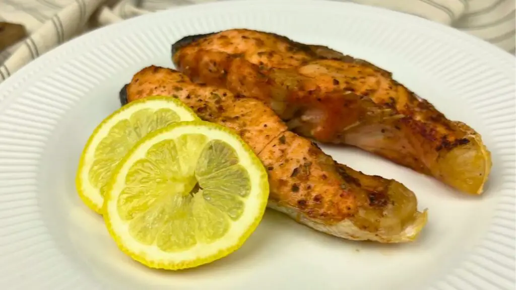 salmon on a plate with fresh lemon slices after cooking.
