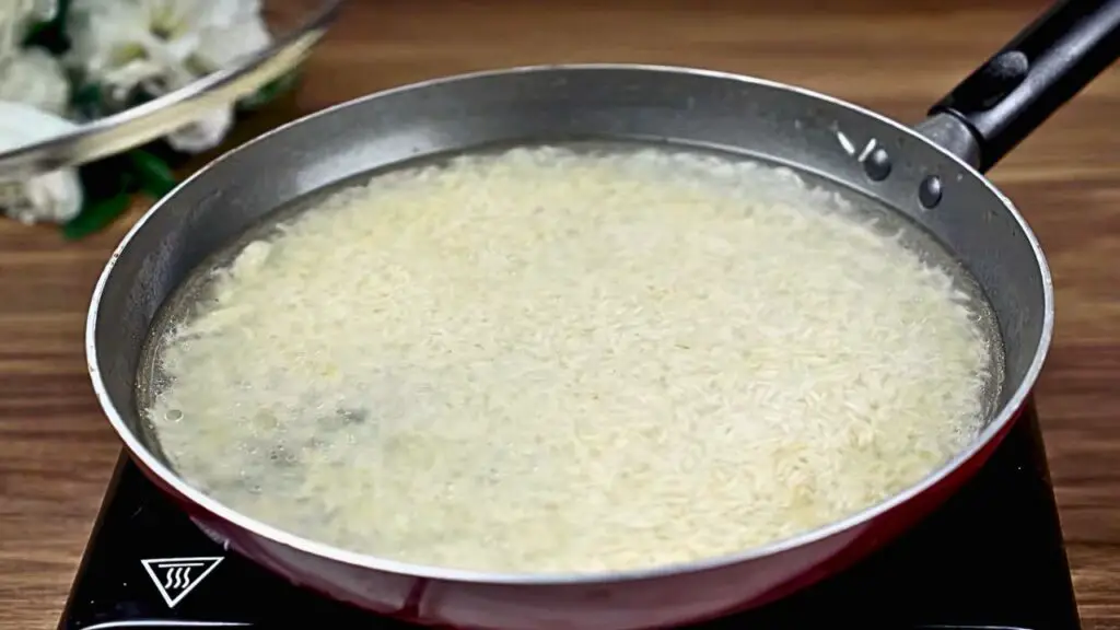 Rice simmering in a pan with water for egg rice recipe until soft and fluffy.