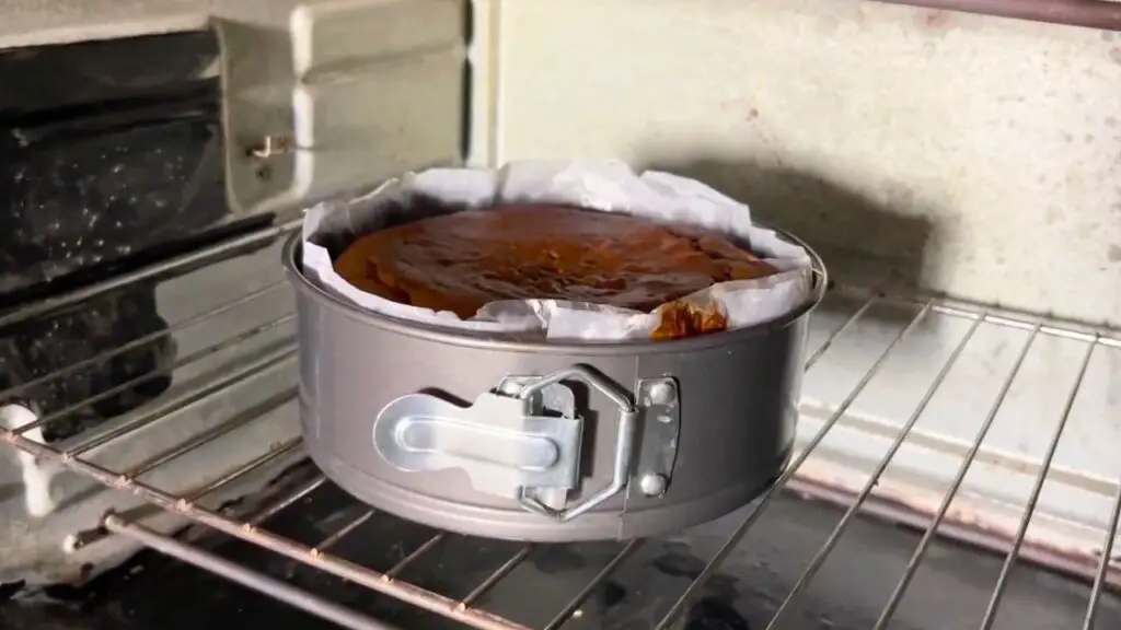 Simple moist date cake recipe baking in the oven in a parchment-lined springform pan until soft, rich, and perfectly set.