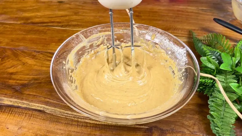Smooth sticky date cake batter being mixed with a hand mixer until thick, creamy, and ready to pour into the baking pan.