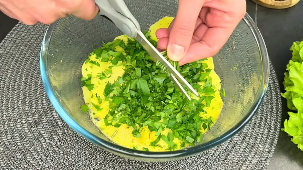 Adding fresh parsley and rosemary to potatoes in air fryer.