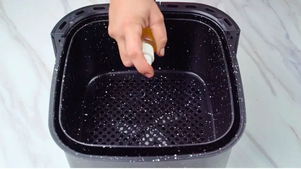 Air fryer chicken thighs with cooking spray applied to the preheated air fryer basket.