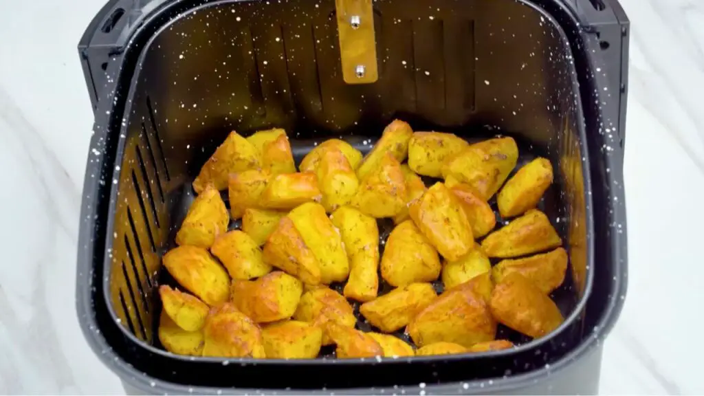 Best roast potatoes air fryer recipe with seasoned potatoes arranged in the air fryer basket before cooking.