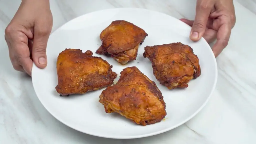 Chicken thighs air fryer recipe served with crispy golden skin on a white plate.