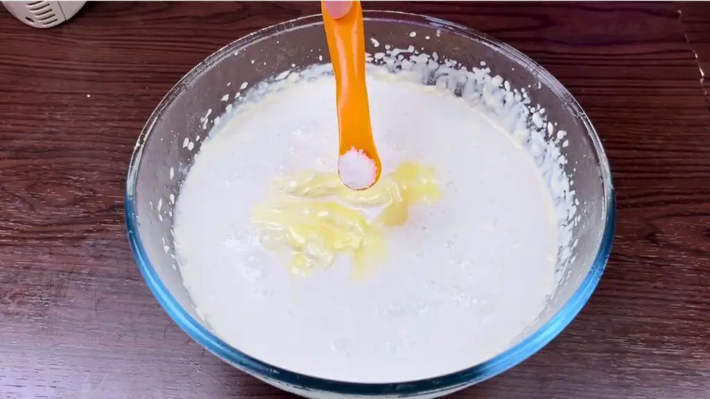 Coconut ice cream recipe with coconut extract and salt being added to the mixture.