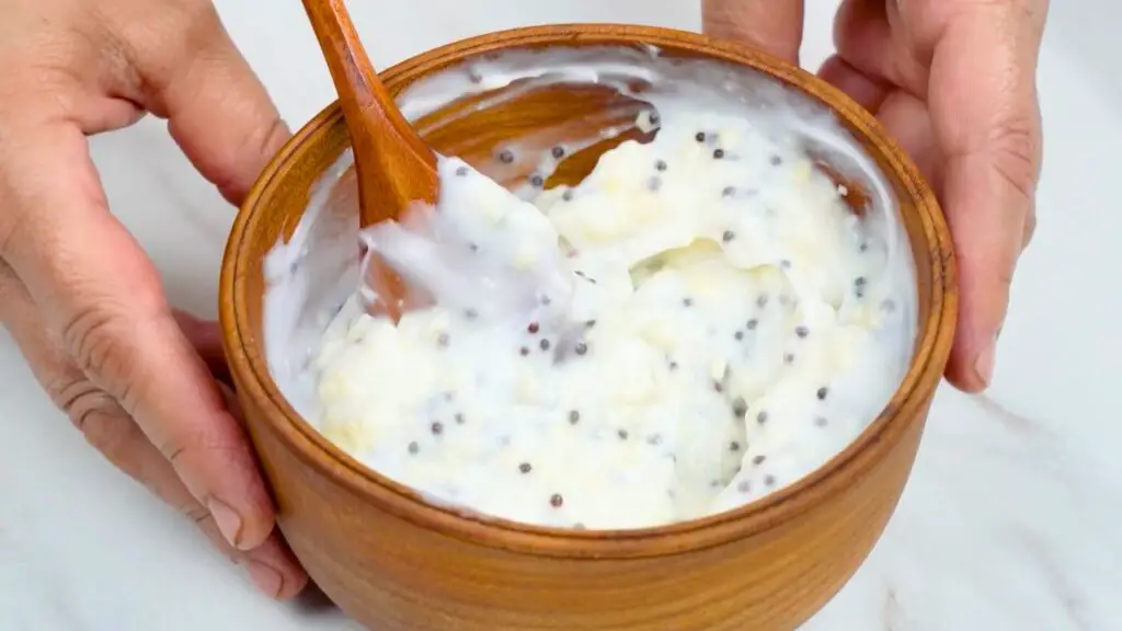 Creamy homemade dipping sauce with visible mustard seeds in a wooden bowl, served as a dip for crispy air fryer onion snacks.