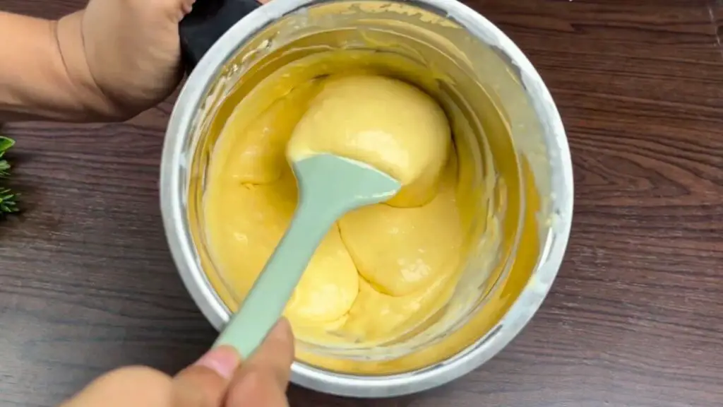 Creamy homemade mango ice cream being scooped from a metal container, showing the smooth, rich texture created by blending mango puree with full-fat cream.