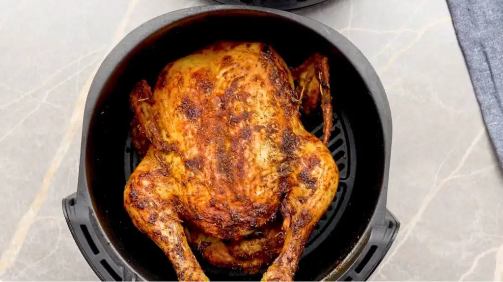 Golden-brown air fryer roasted chicken cooked until crispy on the outside and fully cooked through, resting in the air fryer basket after reaching a safe internal temperature.