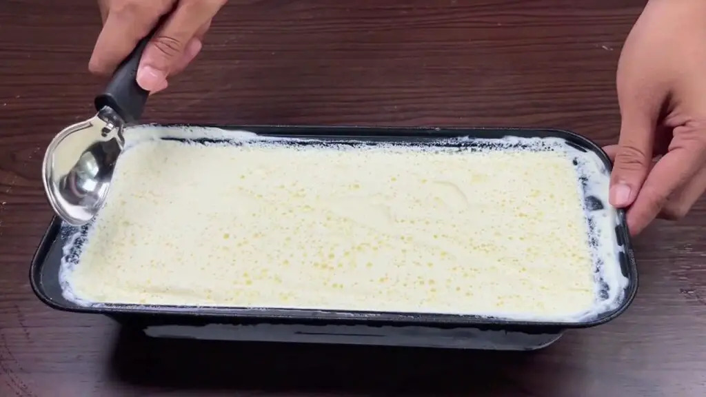 No churn coconut ice cream freezing in a loaf pan before being scooped and served.