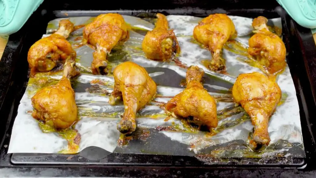 Oven baked chicken drumsticks arranged in a single layer on a parchment-lined baking tray, ready to bake until golden and fully cooked.
