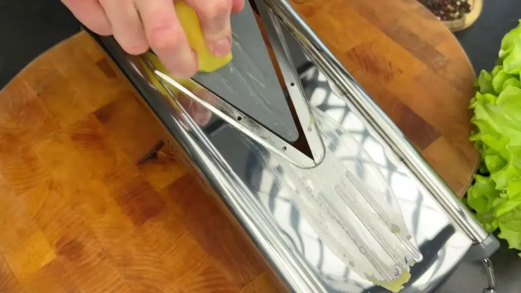 Preparing sliced potatoes in an air fryer using a V-blade slicer.