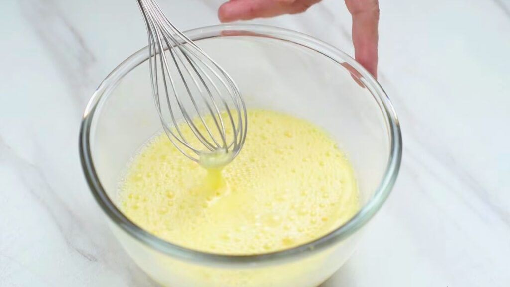 Preparing the egg and buttermilk mixture for how to make crispy chicken.
