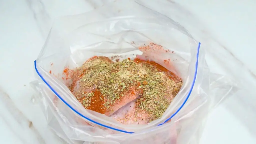 Seasoning chicken thigh in air fryer with spices before cooking..jpg
