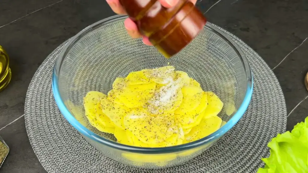 Seasoning potatoes for air fryer sliced potato recipes.
