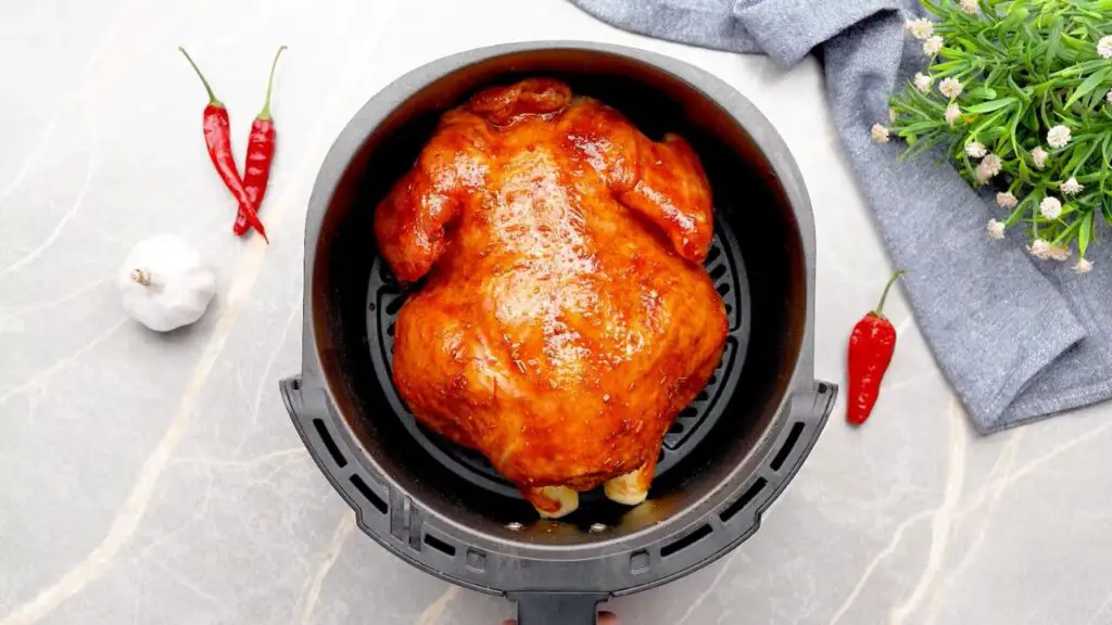 Whole seasoned chicken placed inside an air fryer basket, ready to cook, showing how a whole chicken fits comfortably in the air fryer without overcrowding.