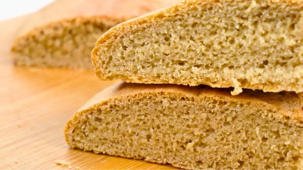 sliced loaf of whole wheat bread showing its soft, textured interior on a wooden cutting board