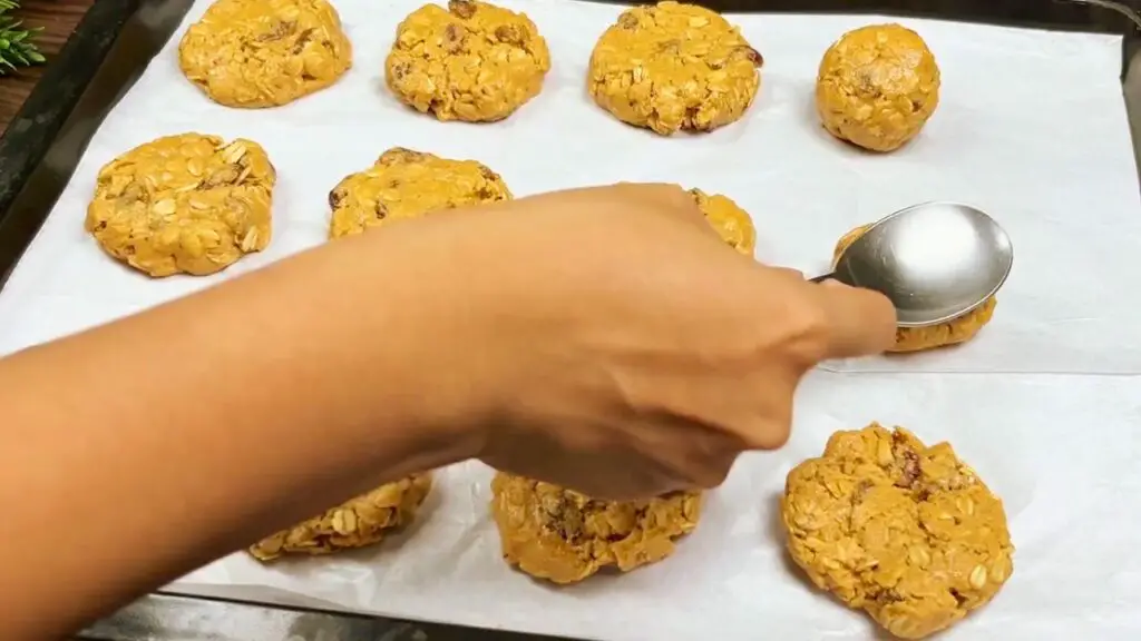 4 ingredient peanut butter cookies with cookie dough gently flattened on a parchment-lined baking tray before baking.