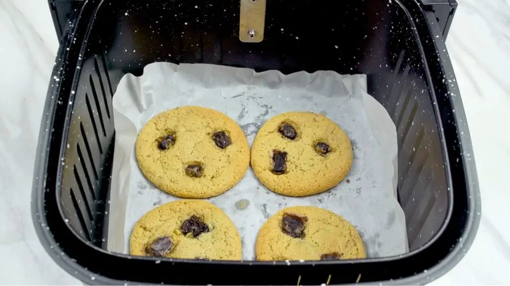 Chocolate chip cookies baked in an air fryer basket until lightly golden, showing soft centers and crisp edges.