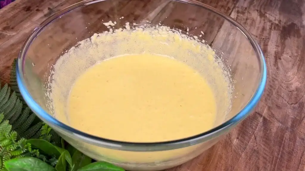 Creamy lemon poppy seed pound cake batter mixed with eggs until smooth and pale in a large glass bowl.
