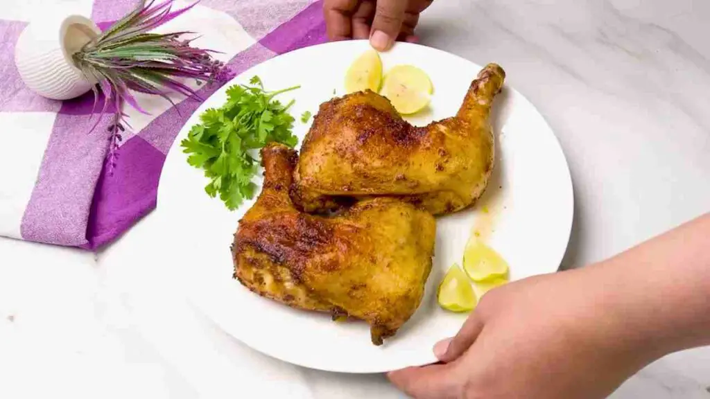 Crispy air fryer chicken legs served on a white plate with fresh parsley and lemon wedges.