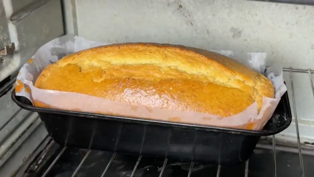 Freshly baked condensed milk cake recipe in a loaf pan cooling after baking.