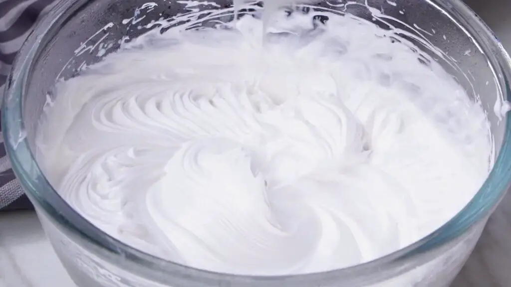 Greek yogurt ice cream whipped cream reaching soft peaks in a chilled glass mixing bowl.