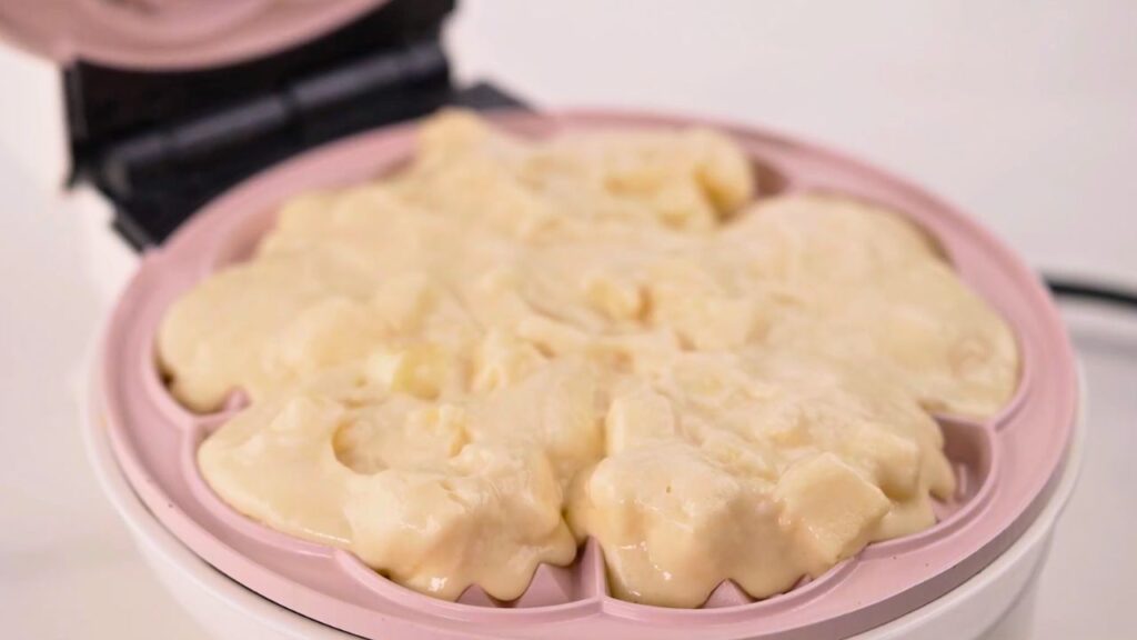 How to make waffles with a waffle iron by spooning apple waffle batter into a preheated waffle maker, spreading it evenly before closing the lid to cook until golden and crisp.