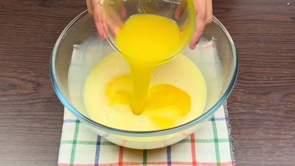 Melted butter being poured into the batter for a condensed milk cake recipe.