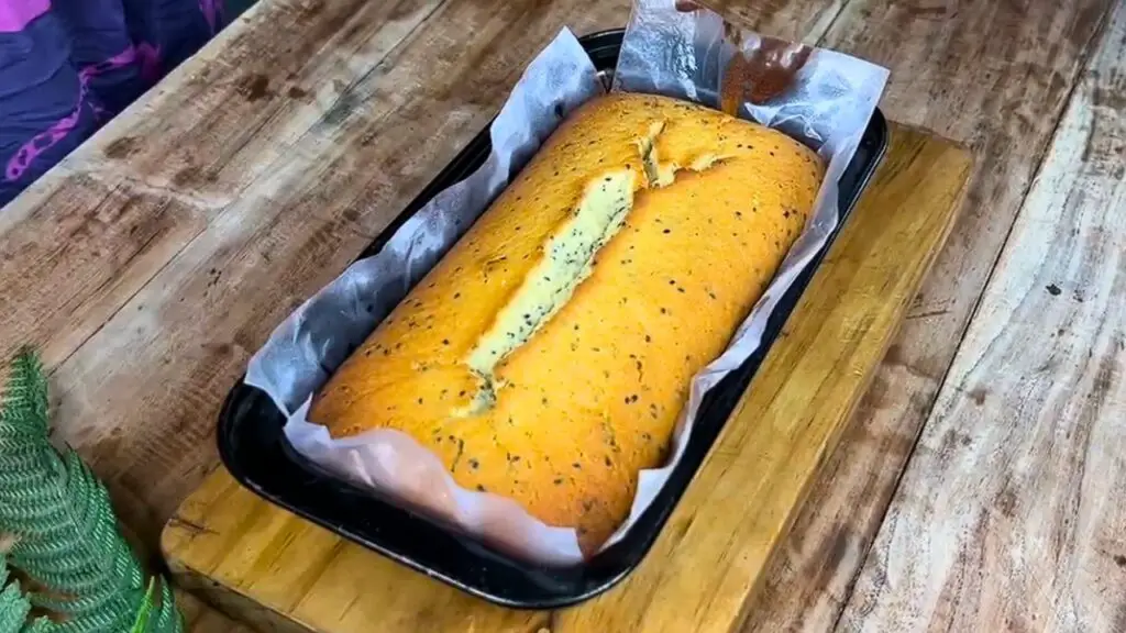 Moist lemon pound cake freshly baked in a loaf pan with a golden crust and classic crack down the center.