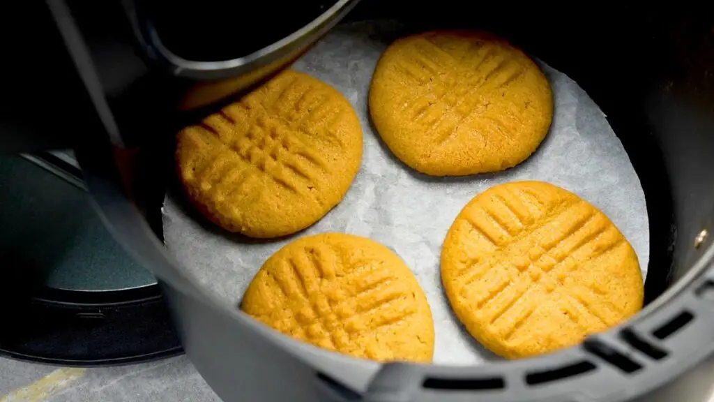 Peanut butter cookies baking in the air fryer with golden edges and classic criss-cross tops.