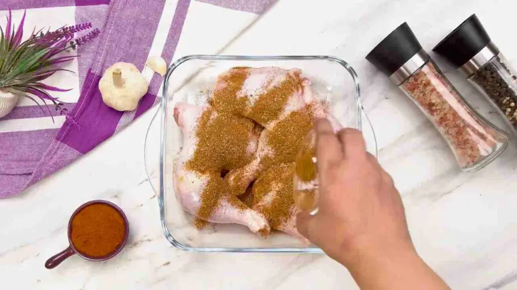 Raw chicken legs coated with seasoning in a glass baking dish before cooking in the air fryer.
