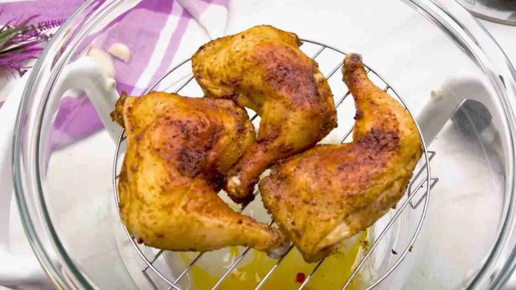 Reheated chicken legs in the air fryer with crispy golden skin inside a glass halogen air fryer.