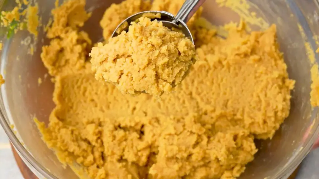 Scoop of peanut butter cookie dough for make-ahead air fryer cookies in a mixing bowl.
