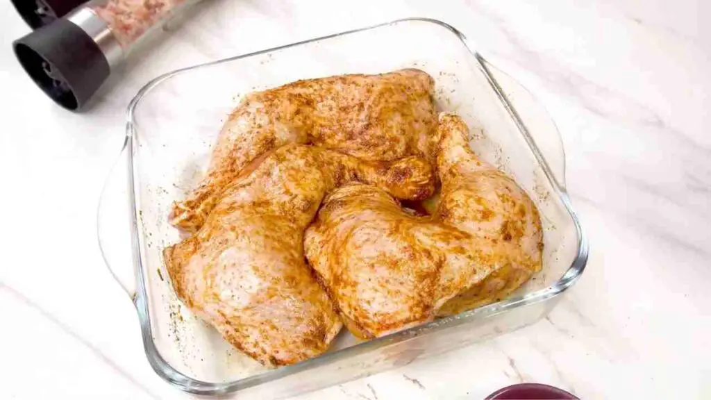 Seasoned raw chicken legs resting in a glass baking dish before cooking crispy air fryer chicken legs.