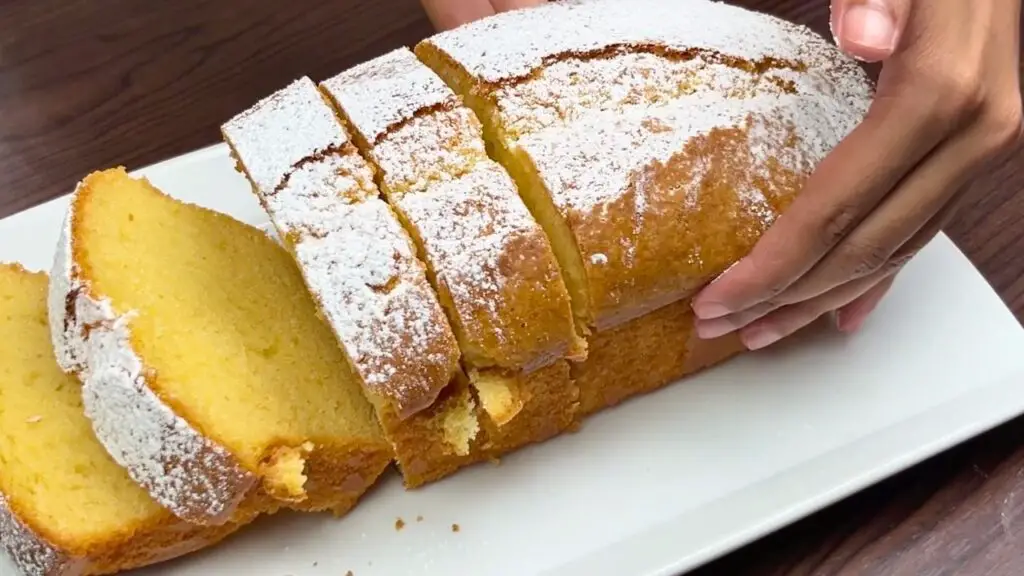 Sliced condensed milk loaf cake dusted with powdered sugar and ready to serve.