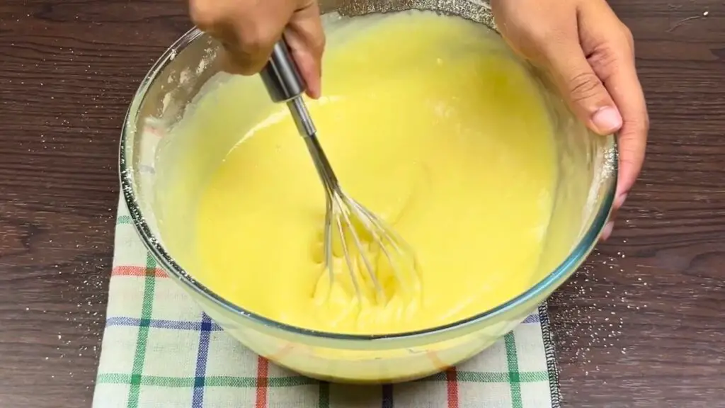 Whisking smooth batter for an easy condensed milk cake before pouring it into the loaf pan.