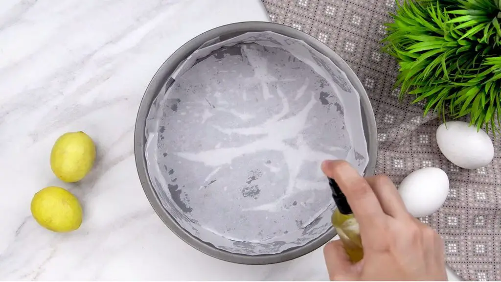 Baking with yogurt starts with preparing a parchment-lined cake pan and lightly greasing the paper to help prevent the yogurt cake from sticking.