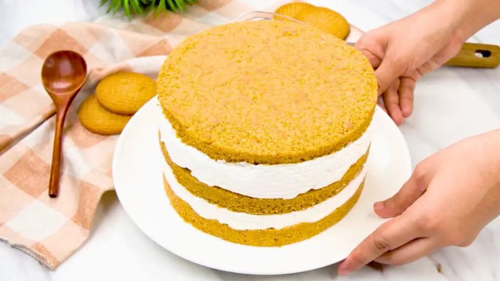 Building the 3 layered cheesecake with alternating biscuit crust and creamy cheesecake filling.