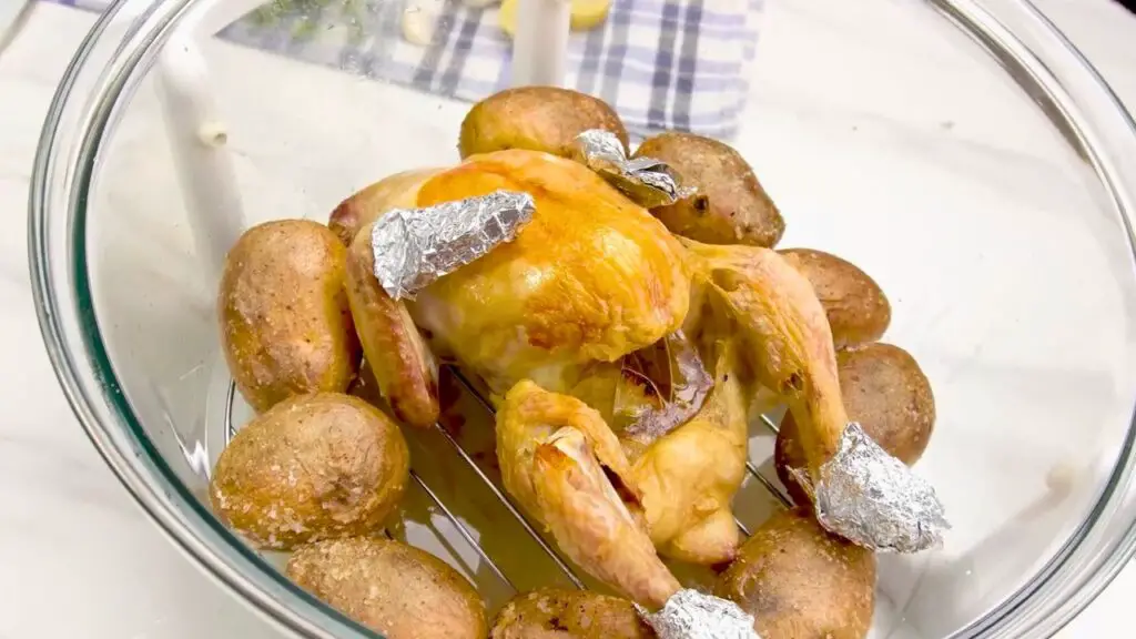 Checking the temperature of a whole chicken cooked in a glass bowl air fryer.