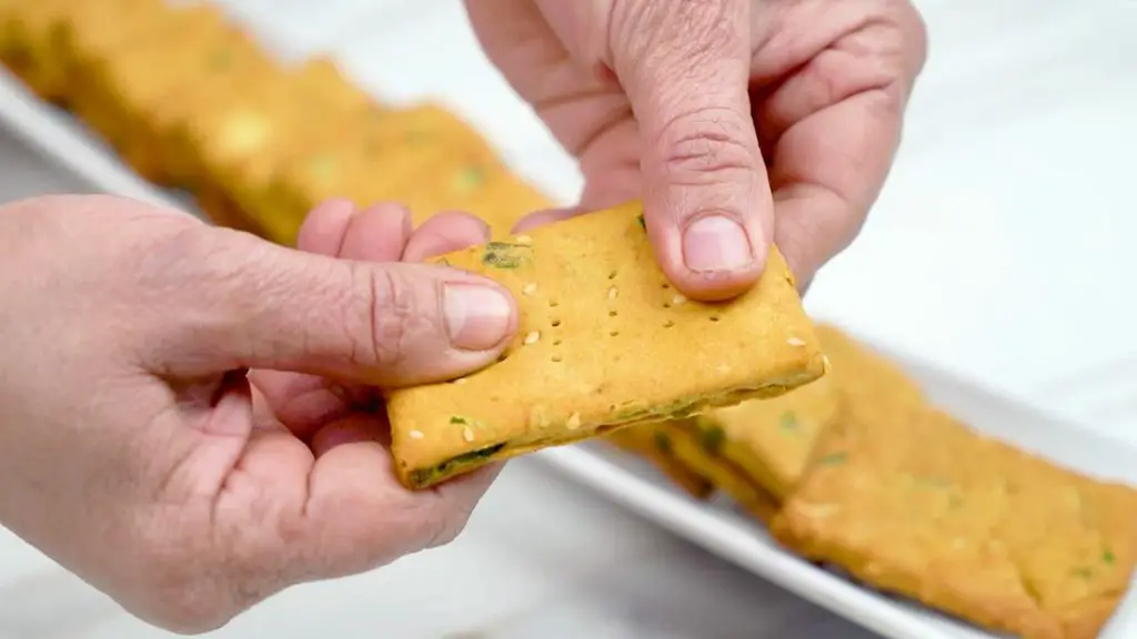 Cracker recipe showing a golden, crispy green onion and sesame cracker after baking.