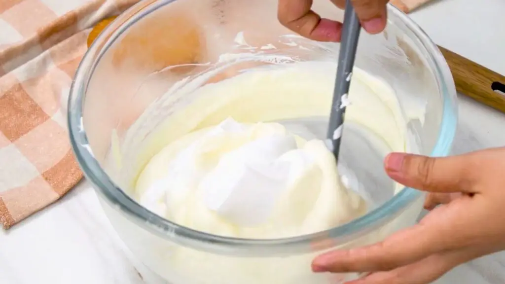 Creamy filling being gently folded together for an extra thick cheesecake recipe.