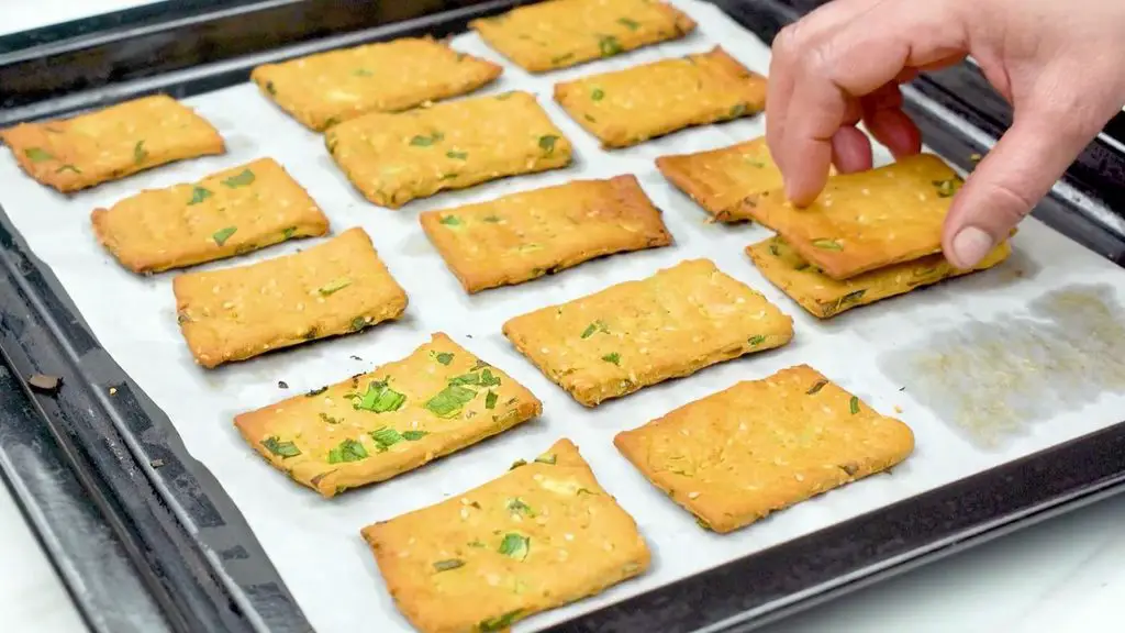 Crispy crackers recipe showing the crackers being put back into the oven to make them crispier.