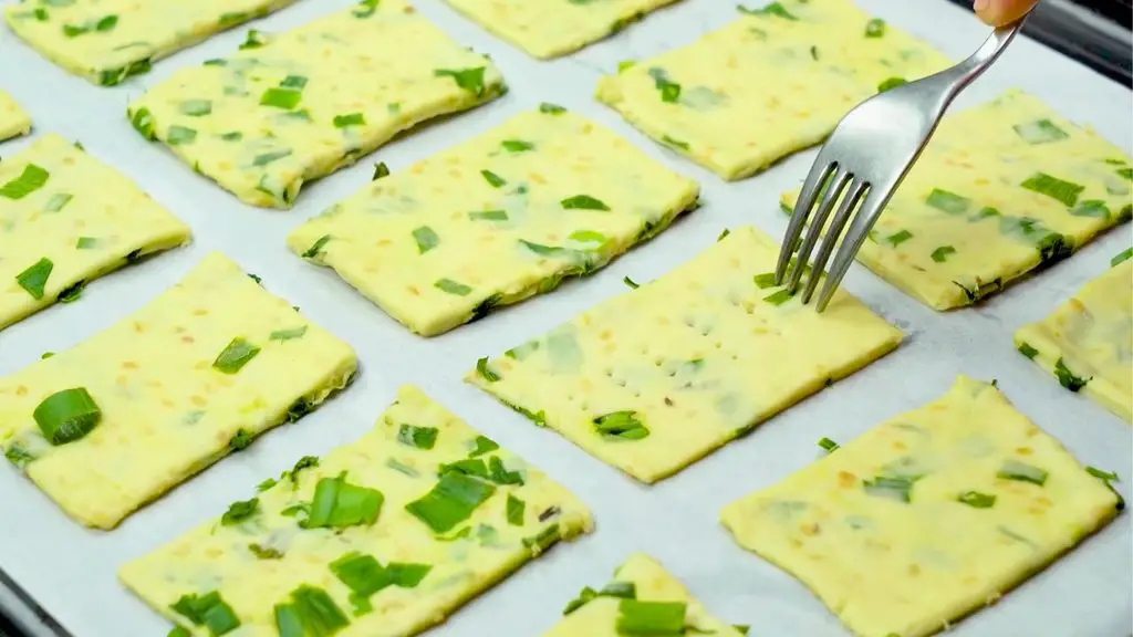 Easy cracker recipe with green onion crackers being poked with a fork before baking.