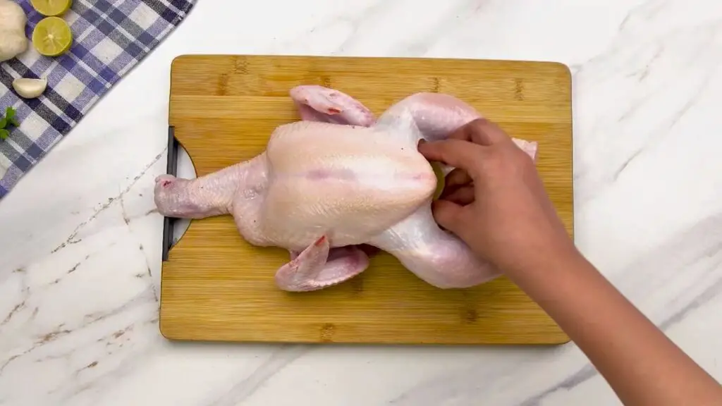 Filling the cavity with lemon, garlic, and sage for air fryer whole chicken.