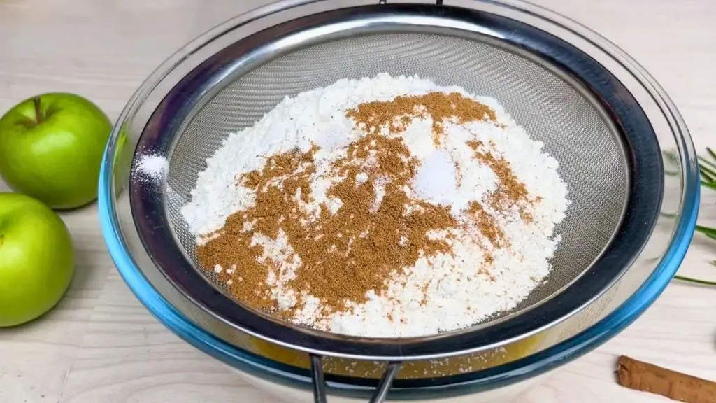 For this apple cinnamon loaf cake recipe, sift the flour, cinnamon, baking powder, baking soda, and salt together so the dry ingredients mix evenly into the batter.