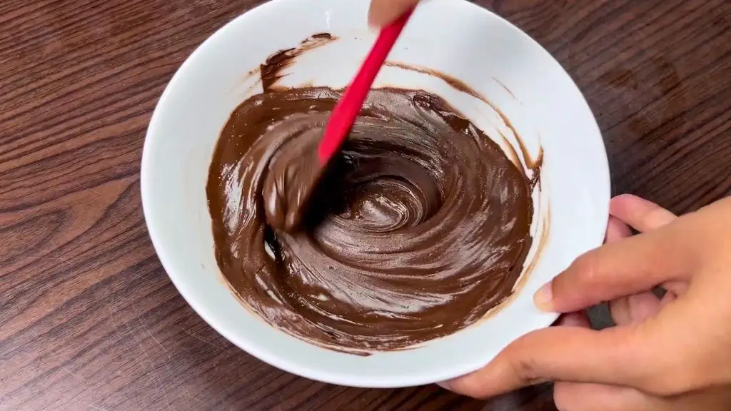 Fudgy brownies recipe showing melted semi-sweet chocolate stirred until smooth and glossy.