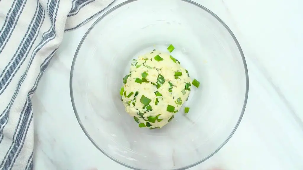 Green onion cracker dough mixed with sesame seeds and shaped into a smooth ball.