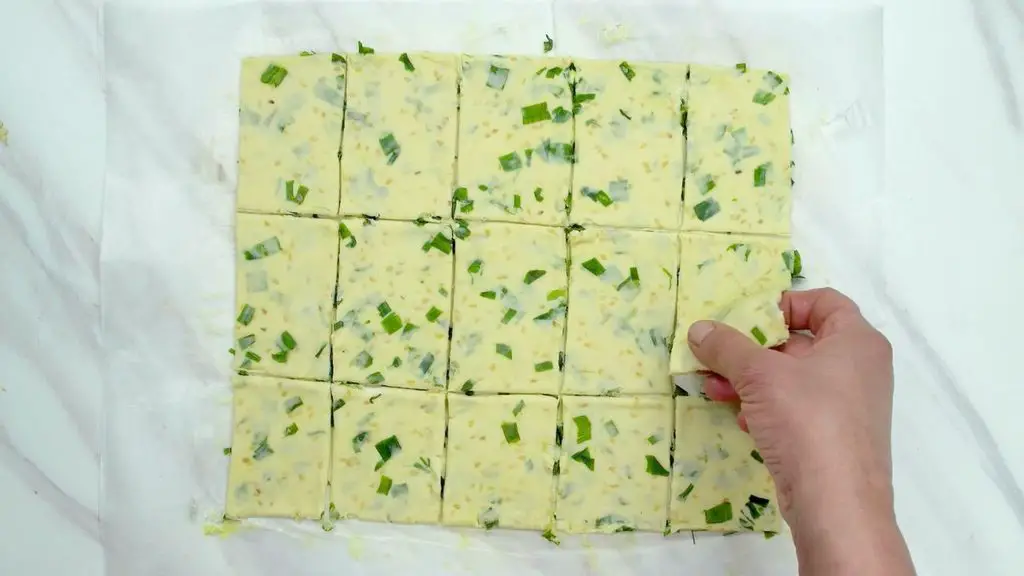 Homemade crackers recipe with green onions and sesame seeds cut into small rectangles.